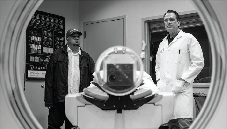 Black and white photograph of Jaime Tafoya and a doctor looking into an MRI machine for the documentary Stroke: The Circle of Healing.