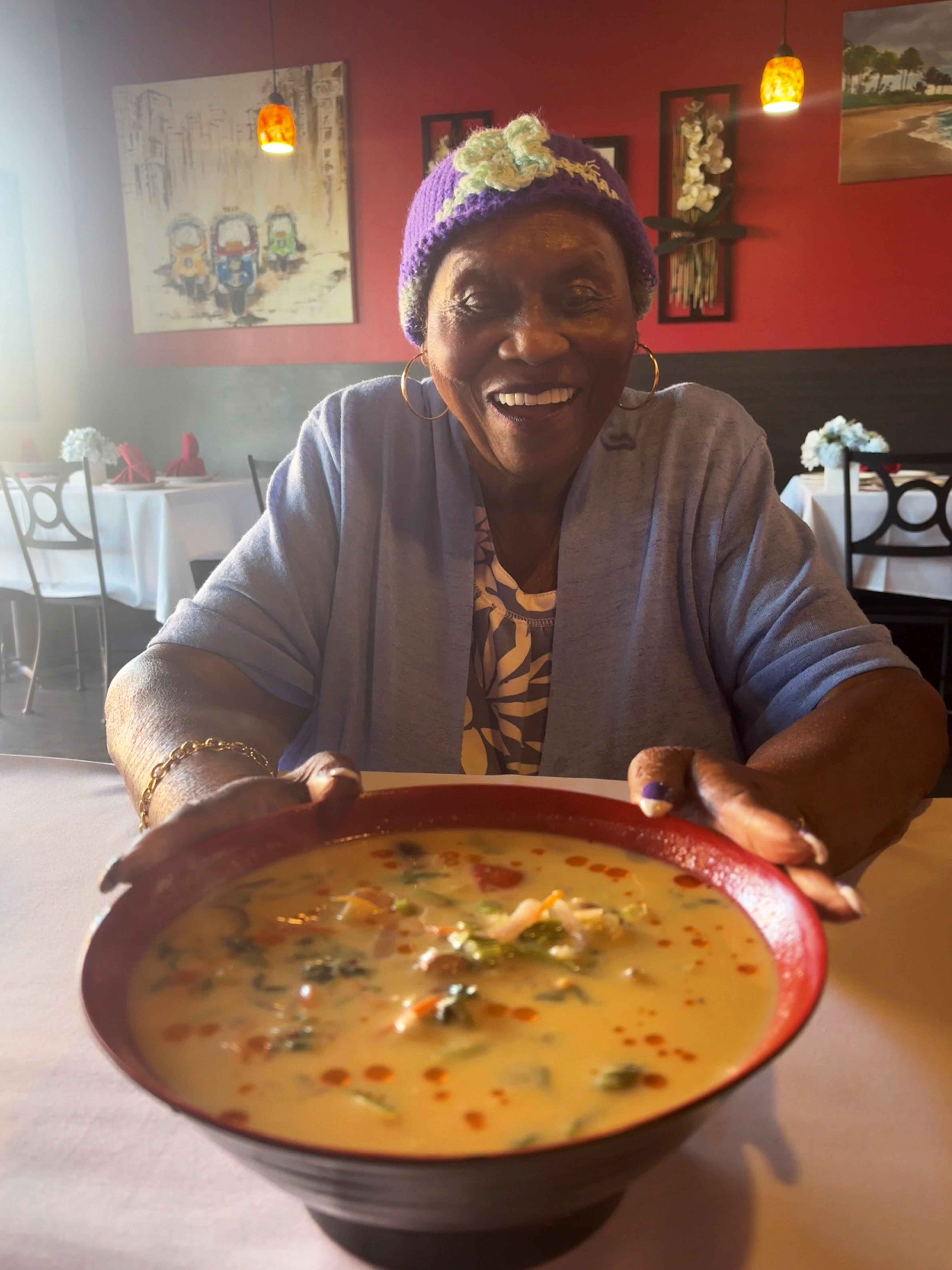 Ruby Duncan holding a bowl of spicy Thai soup in a restaurant
