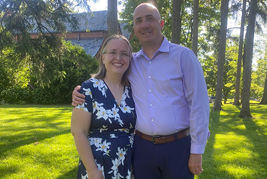 Lauren Emanuelson and her significant other posed for a photo with green grass a tress in the background