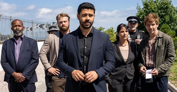 Group of people standing outdoors, including two in police uniforms and others in casual and formal attire.