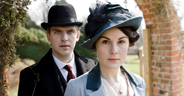Dan Stevens as Matthew Crawley and Michelle Dockery as Lady Mary Crawley standing outside in an archway.