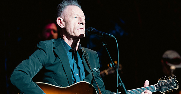 Lyle Lovett performs songs from Bruce Springsteen’s 1982 album Nebraska on Stage in front of musicians.