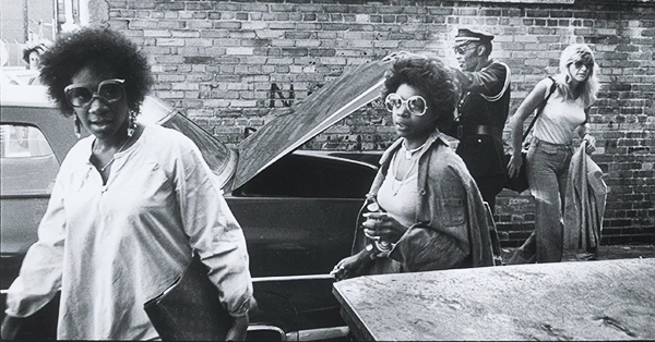 Vicki Wickham, Pattie Labelle, Sarah Dash in 1975. Standing in front of a brink wall and a car with the truck lid open.