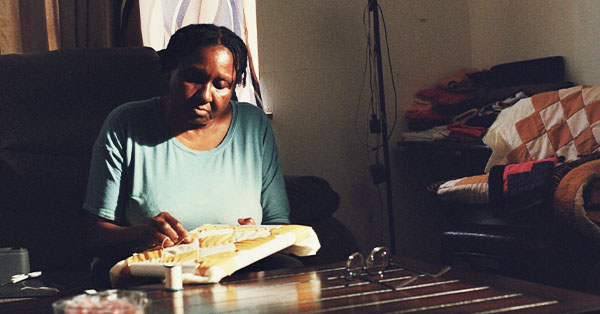 Caster Pettway, a renowned quiltmaker from Gee's Bend, hand stitches a quilt, continuing the tradition that has been passed down through generations.