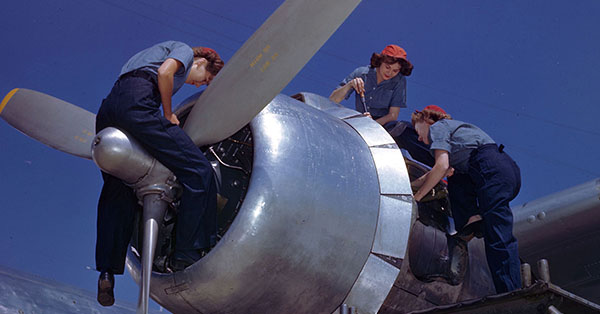 Women working on a war plane engine.