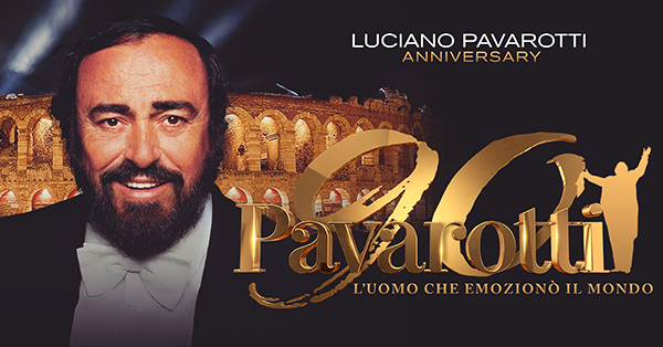 Promotional image for Pavarotti 90: The Man Who Moved the World featuring Luciano Pavarotti smiling in formal concert attire. An illuminated opera arena appears in the background, with the program title displayed in large gold lettering.