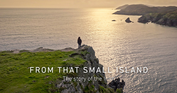 Promotional image for From That Small Island showing a person standing on a grassy cliff overlooking the ocean at sunset. The coastline stretches into the distance, and the title 