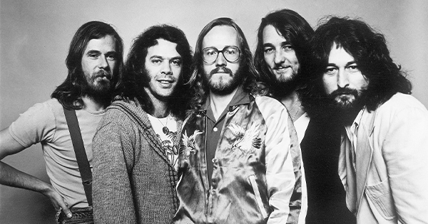 Promotional image of the five members of Supertramp posing together for a black-and-white group portrait. The band members stand shoulder to shoulder, looking toward the camera in a classic publicity photo.